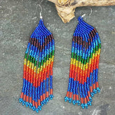 Colorful beaded earrings on a dark surface