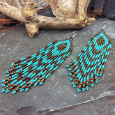 Beaded earrings with turquoise and brown beads on a stone surface.
