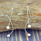 Silver earrings with spherical ends on a wooden surface