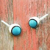 Pair of turquoise stud earrings on a wooden surface
