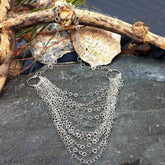 Silver chain necklace on a stone surface with natural elements