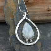 Silver teardrop pendant with a light blue Moonstone on a stone surface