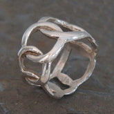Silver ring with intricate design on a textured surface