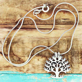 Silver Snake Chain with a tree-shaped pendant on a wooden surface