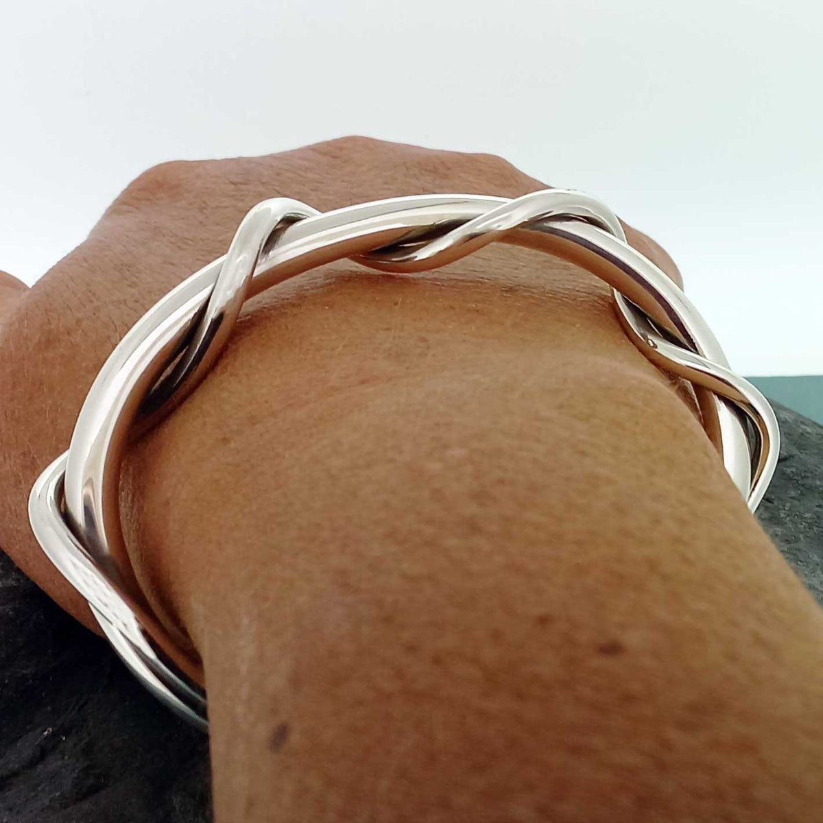 Silver bracelet on a wrist with a neutral background