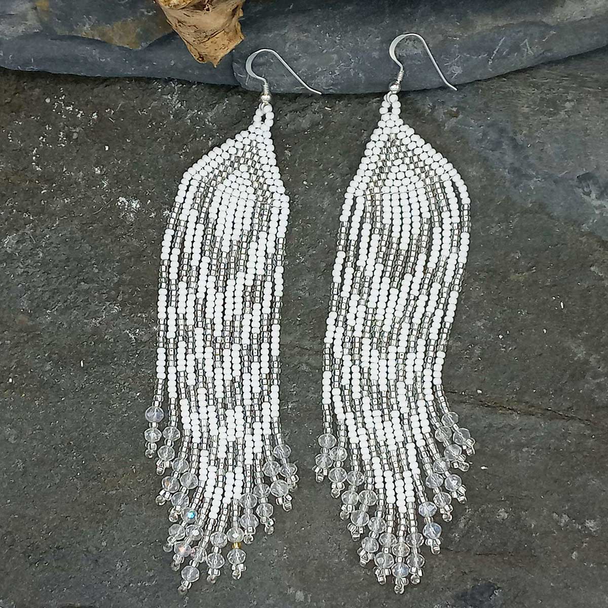 Pair of beaded fringe earrings on a dark stone surface