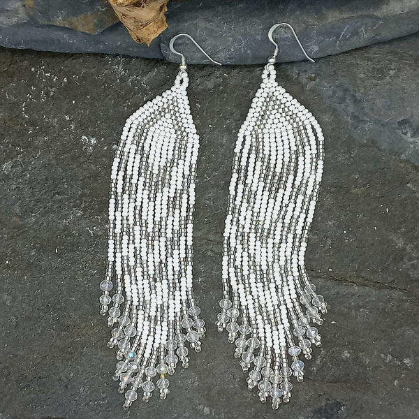 Pair of beaded fringe earrings on a dark stone surface
