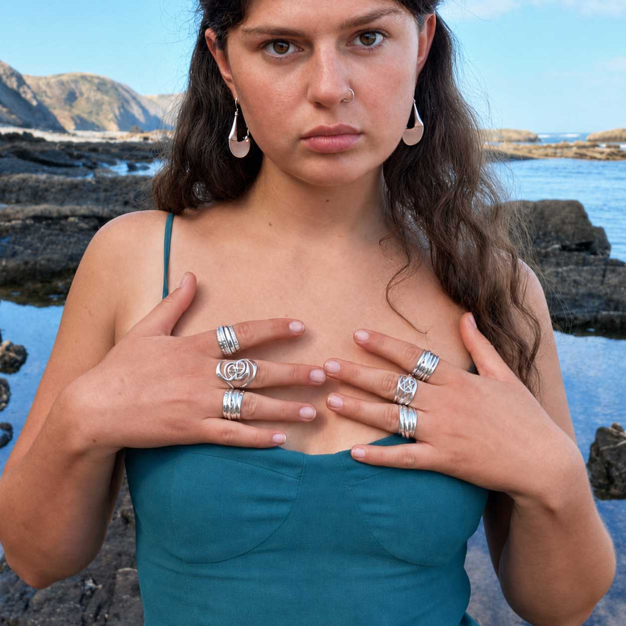 Woman wearing collection of Silver Bubble chunky sterling silver handmade rings on beach.