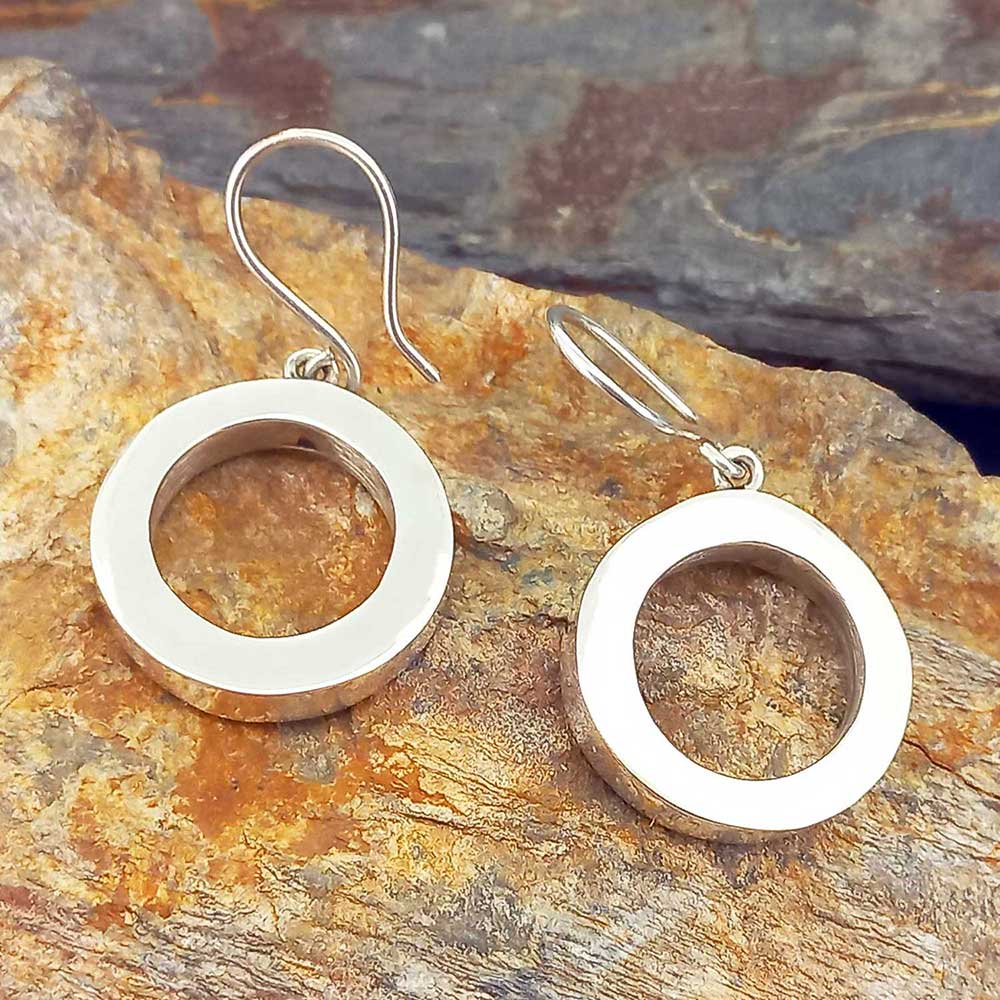 Silver circular earrings on a stone surface