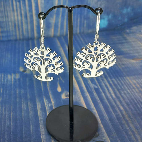 Silver tree-shaped earrings on a blue wooden background