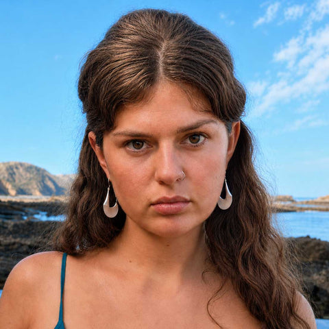 Woman wearing tribal influenced unusual silver statement earrings.