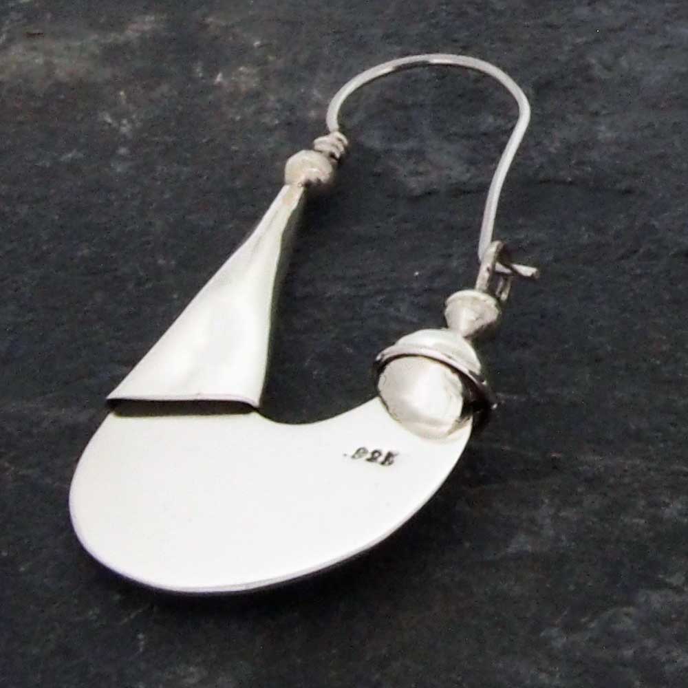 Silver earring with a teardrop shape on a dark background