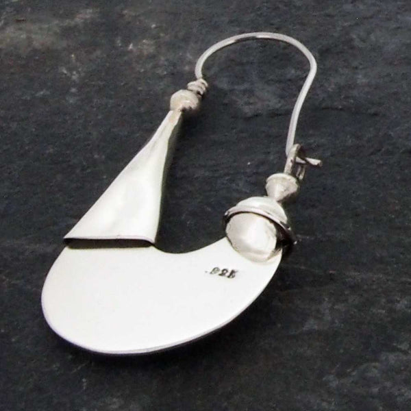 Silver earring with a teardrop shape on a dark background