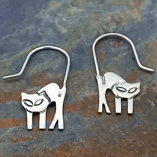 A pair of sterling silver earrings in the shape of cats with hooks for ears.