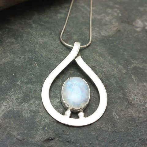 Teadrop handcrafted silver pendant with a moonstone on a dark stone surface
