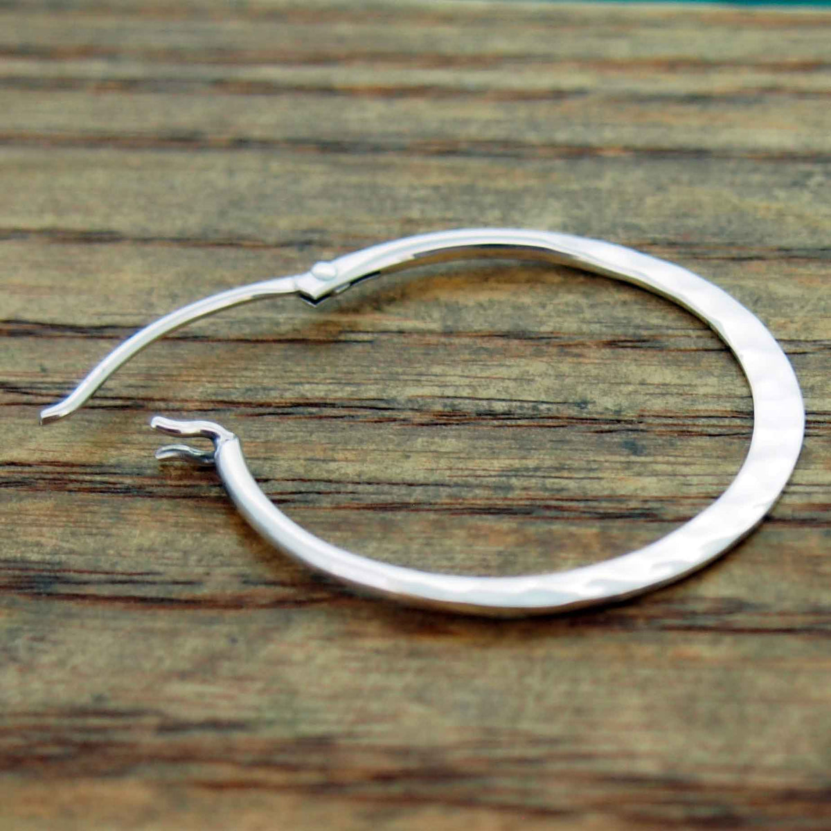 Silver hoop earrings on a wooden surface