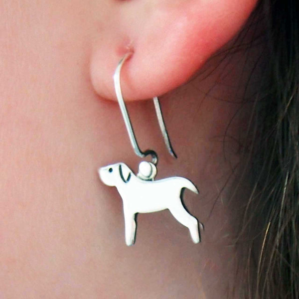 Silver dog-shaped earrings worn by a person.