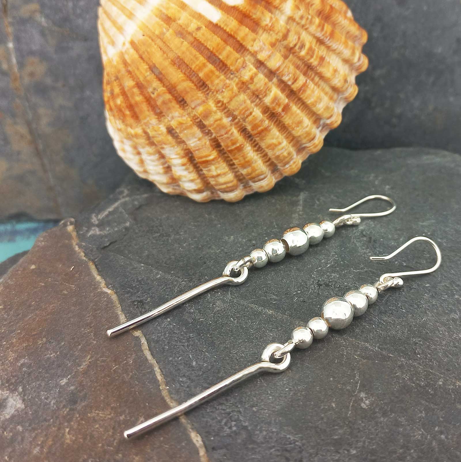 A pair of unusual silver drop earrings with small spherical beads and a long straight bar