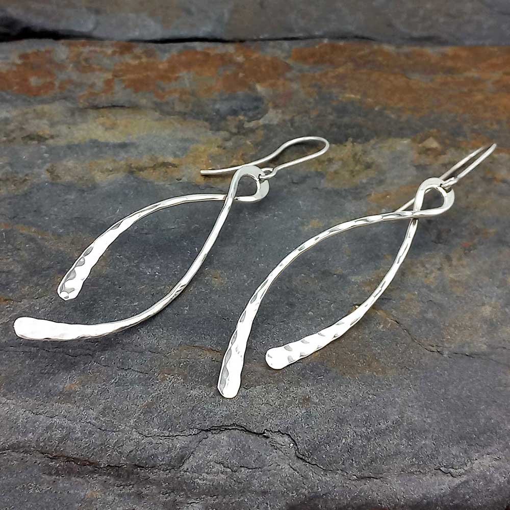 Silver dangle earrings on a textured stone surface