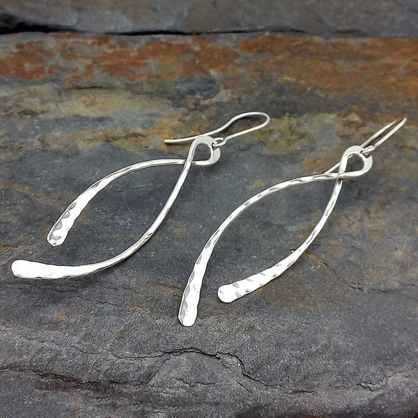 Silver dangle earrings on a textured stone surface