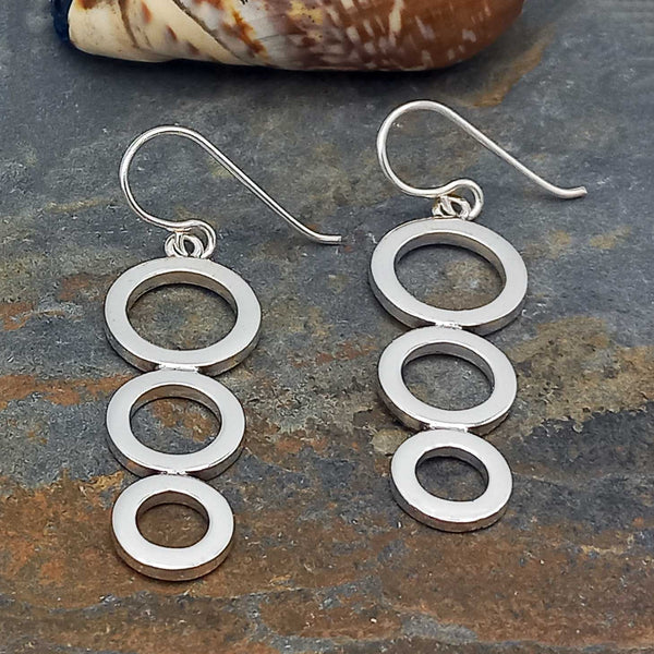 Silver circular earrings on a textured stone surface