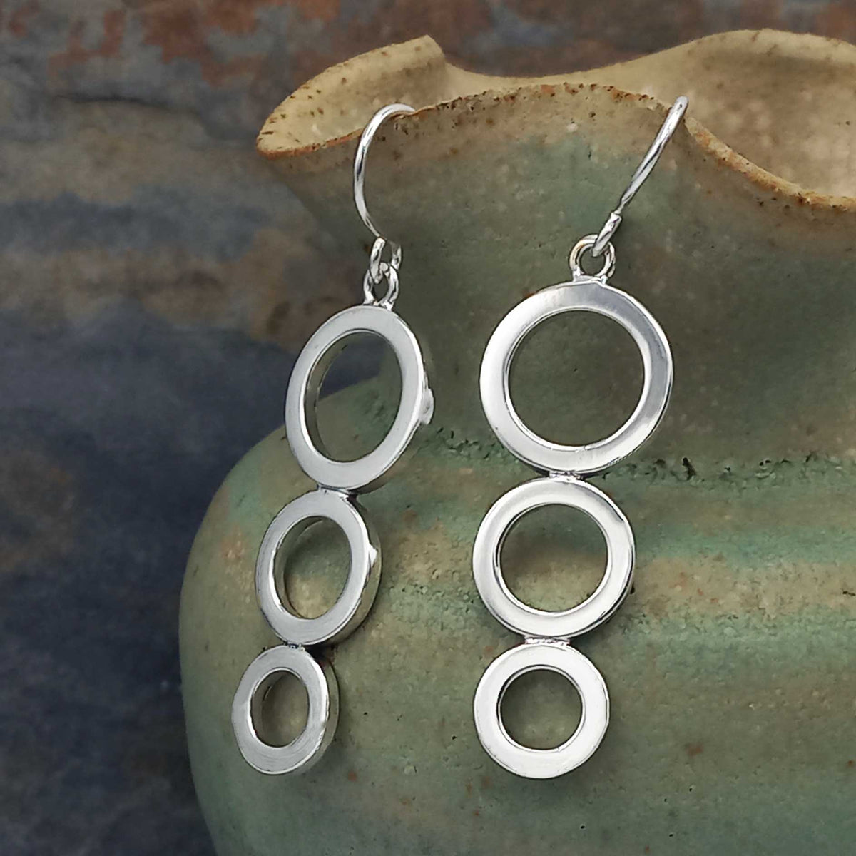 Silver circular earrings on a textured green surface
