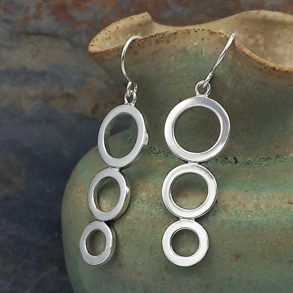 Silver circular earrings on a textured green surface