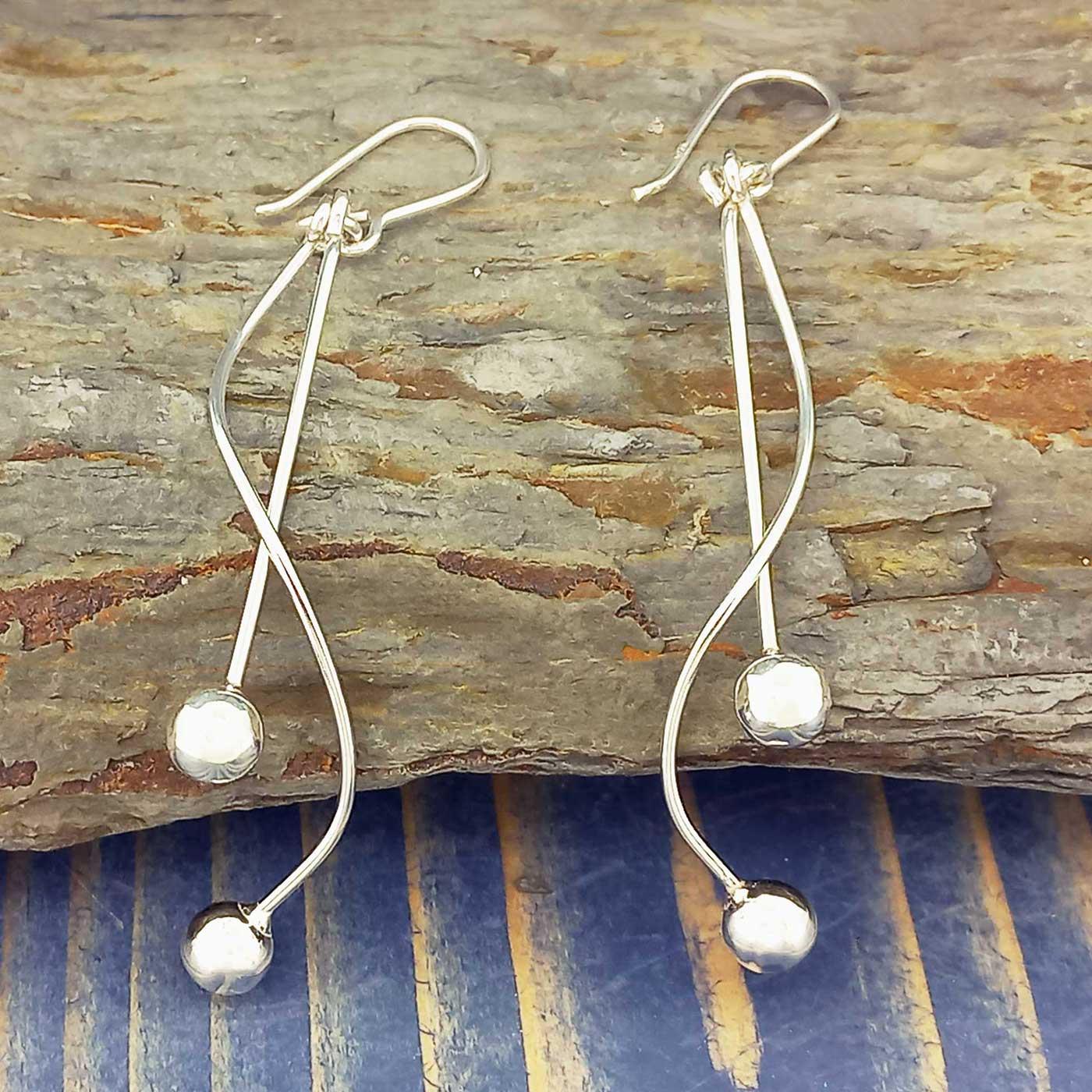 Silver earrings with spherical ends on a wooden surface