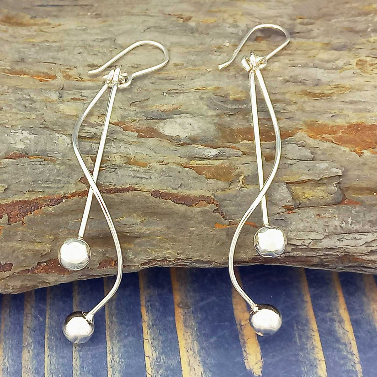 Silver earrings with spherical ends on a wooden surface