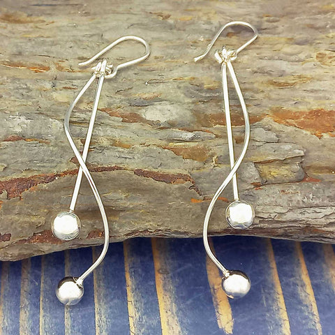 Silver earrings with spherical ends on a wooden surface