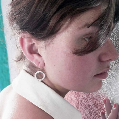 Close-up of a person wearing a circular earring with a blurred background