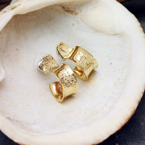 Gold hoop earrings on a seashell