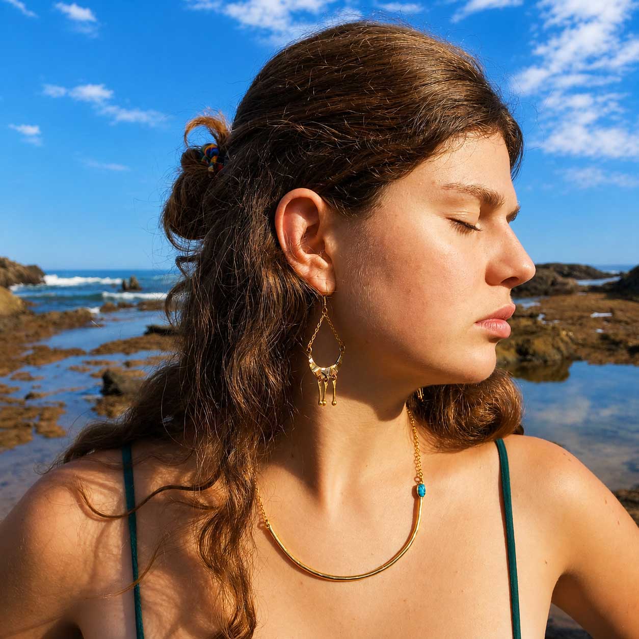 Turquoise Aviva gold brass unusual necklace worn by woman at ocean
