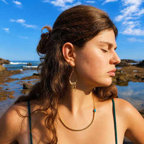 Turquoise Aviva gold brass unusual necklace worn by woman at ocean