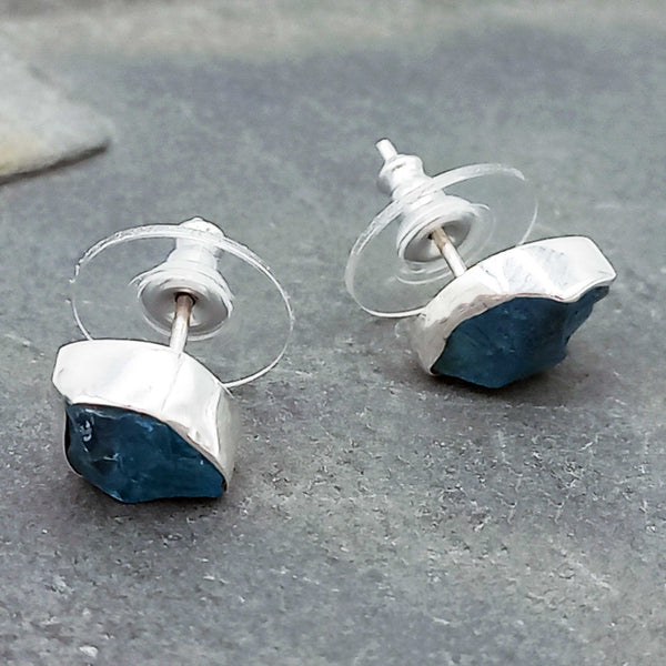 Silver and blue stud earrings on a gray stone surface