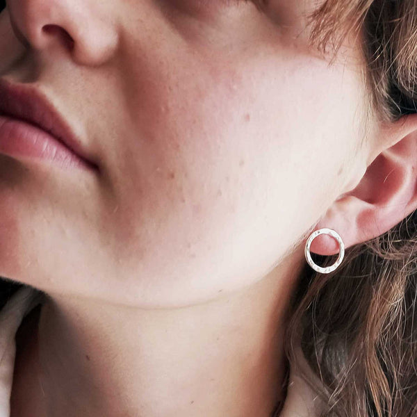 Close-up of a person wearing a silver circle stud earring.