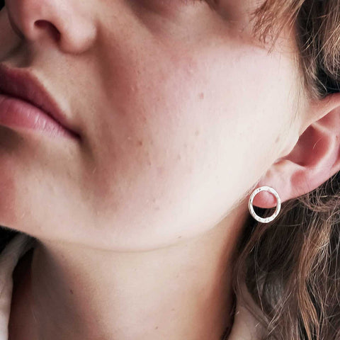 Close-up of a person wearing a silver circle stud earring.