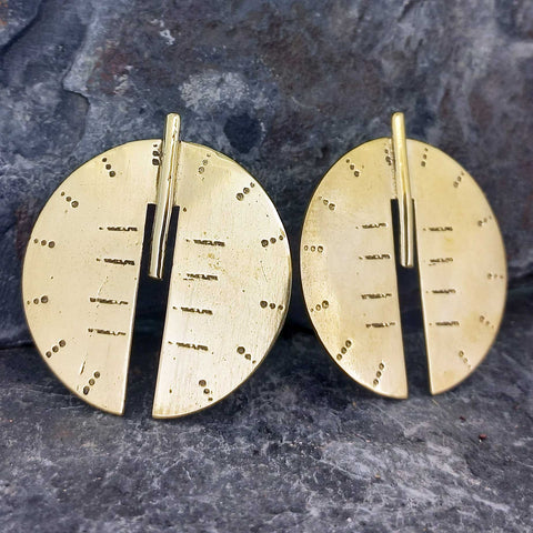 A pair of statement gold-toned disc stud earrings with a split circular design, textured surface, and small dot details.