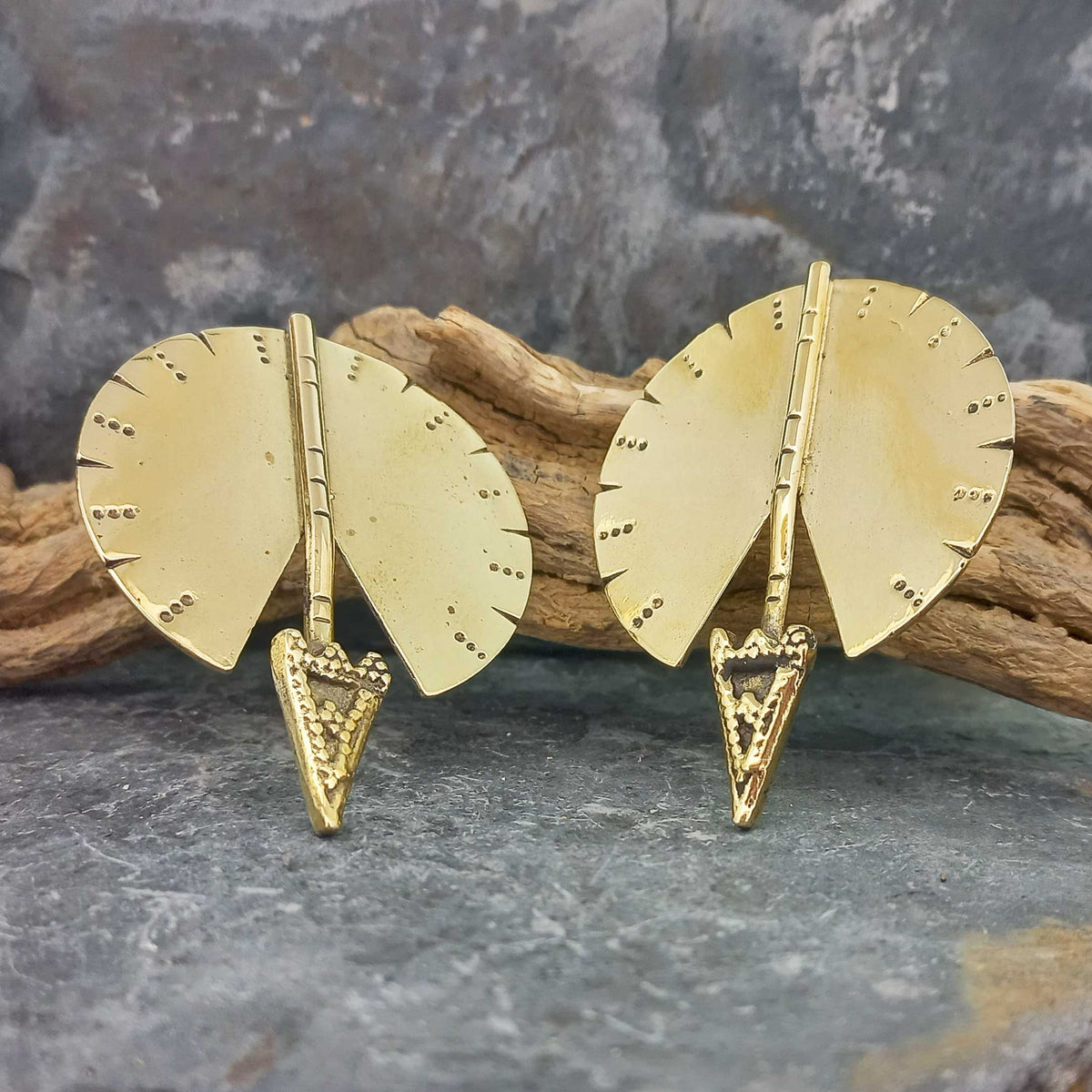 A pair of gold-toned arrow-shaped unusual stud earrings with fan-shaped backplates and textured triangular tips.