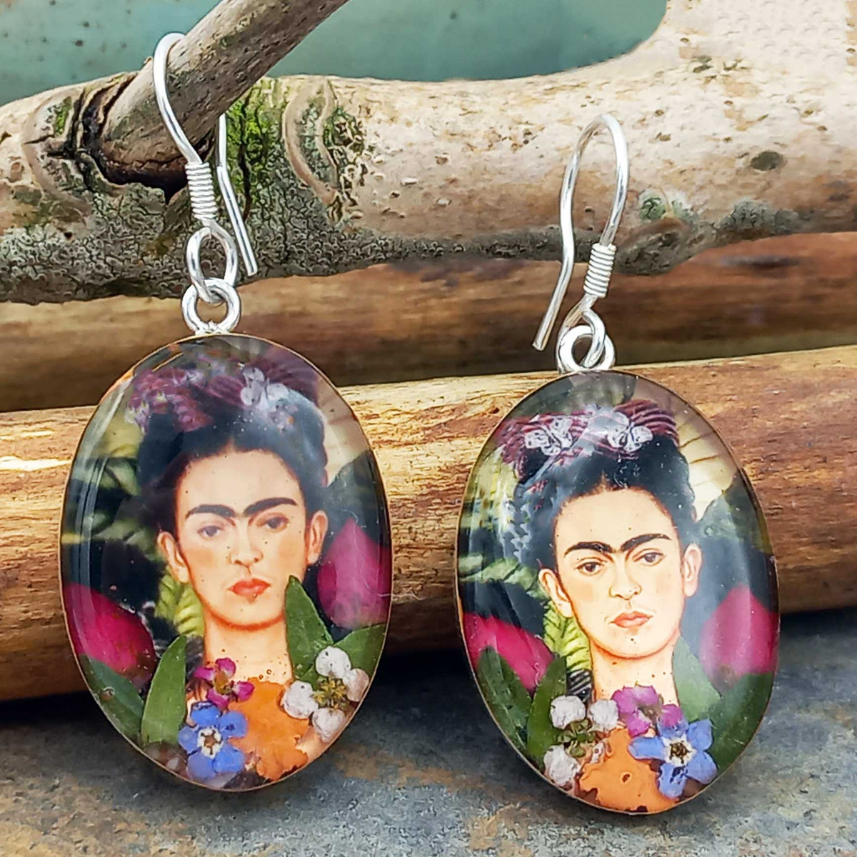 Frida Kahlo earrings with floral details on a wooden background