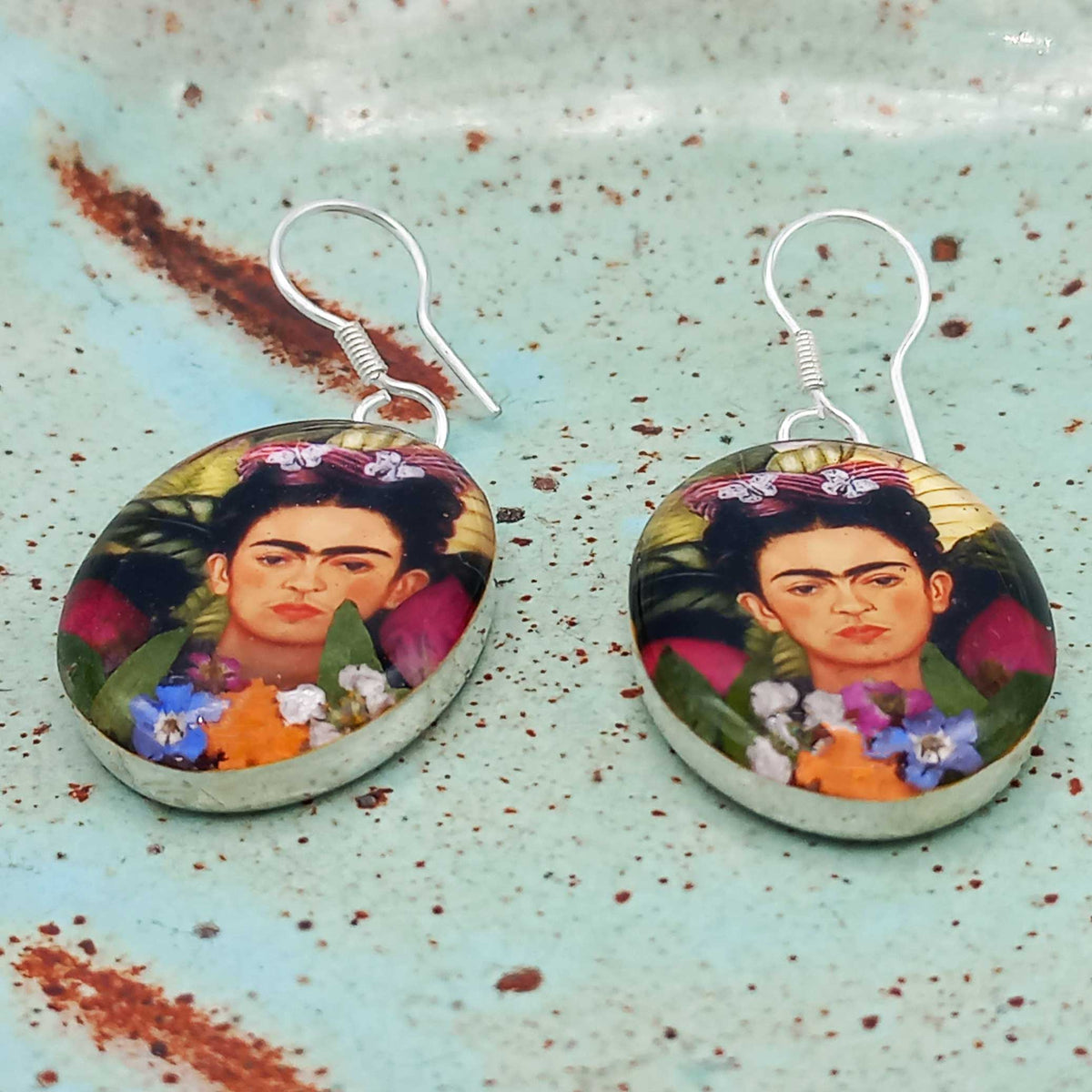 Frida Kahlo sterling silver earrings on a textured surface