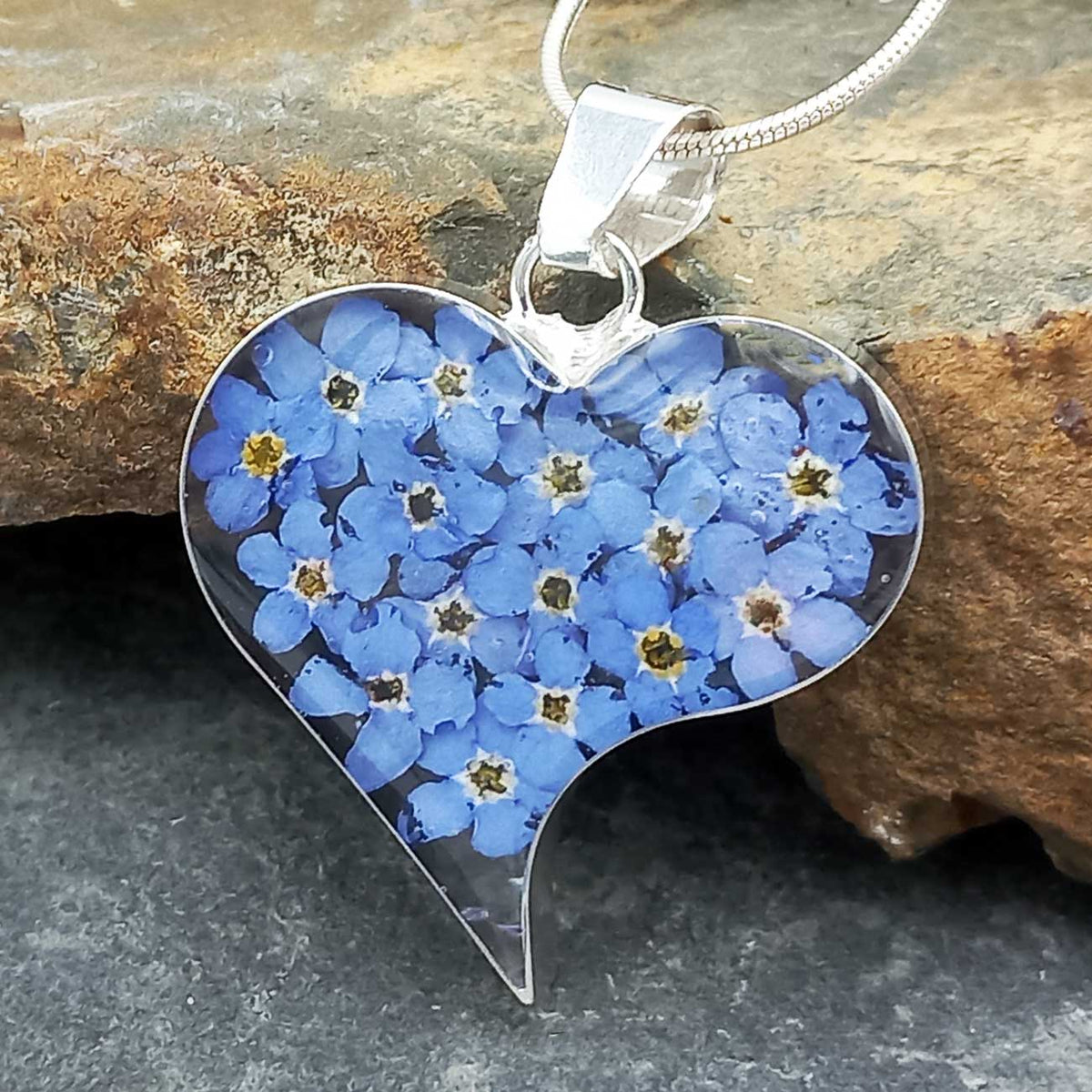 Heart-shaped pendant with blue flowers on a stone background