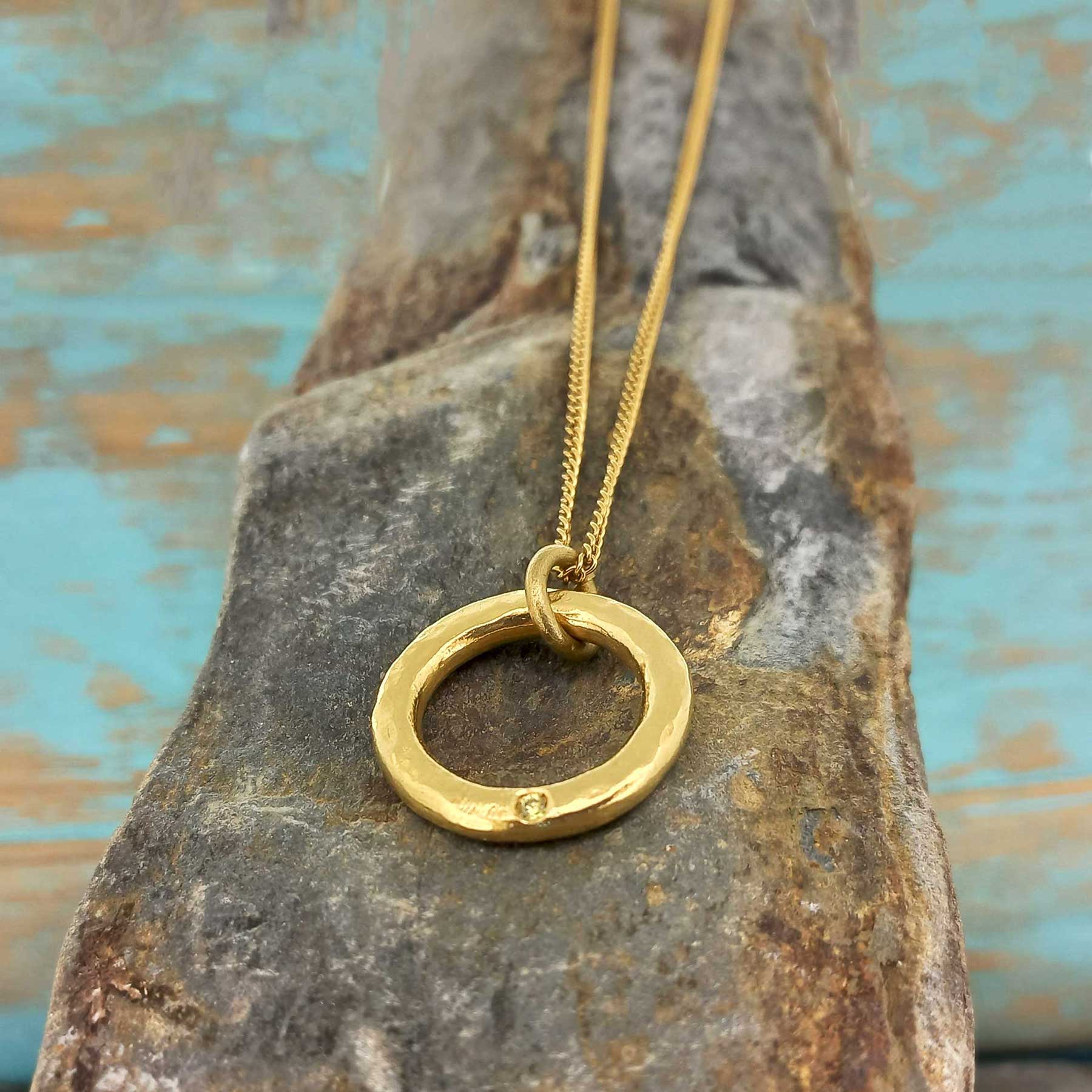 Gold coloured necklace with a circular pendant with white glass cabochon