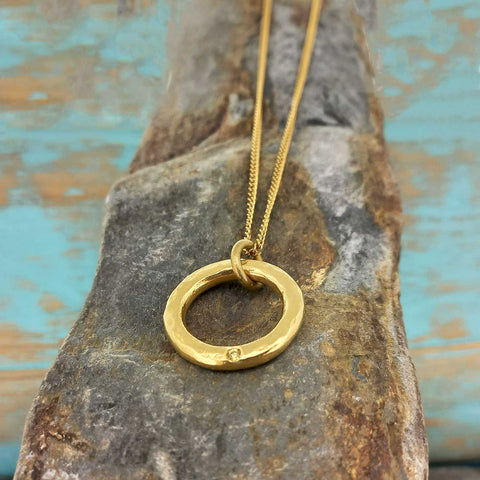 Gold coloured necklace with a circular pendant with white glass cabochon