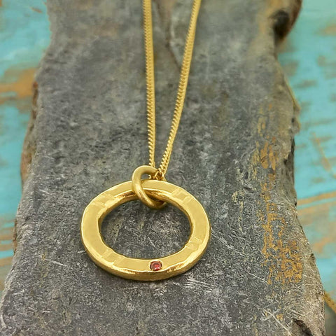 Gold colored hammered circle necklace wth red glass cabochon