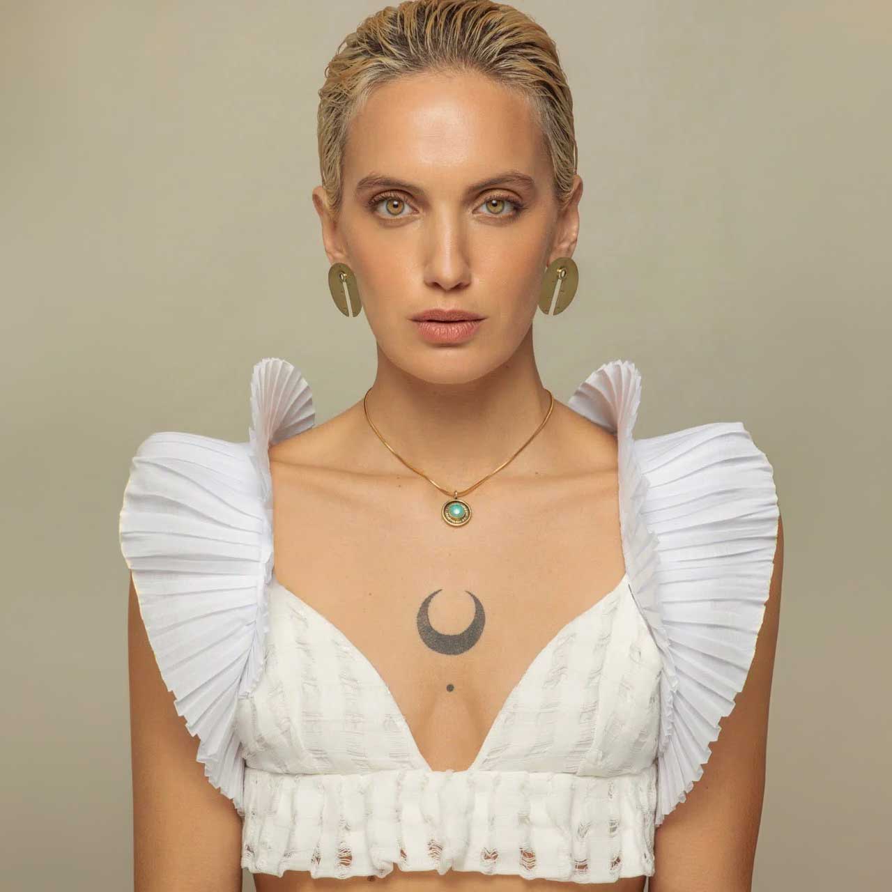 Woman wearing statement studs and brass necklace