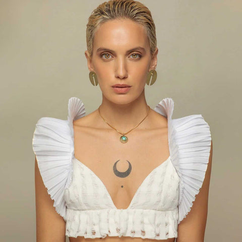 Woman wearing statement studs and brass necklace