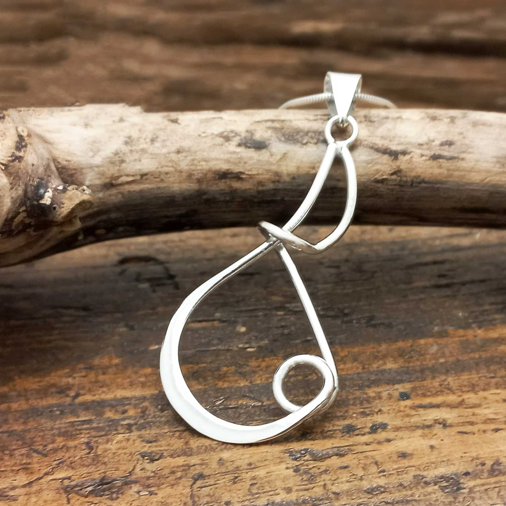 Silver artisan pendant on a wooden surface