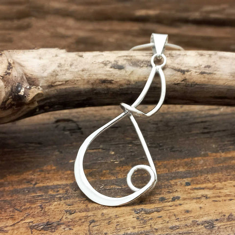 Silver artisan pendant on a wooden surface