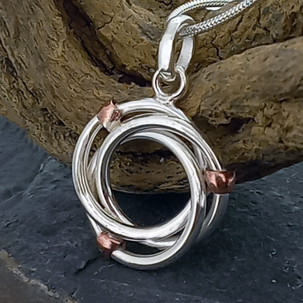 Silver and copper pendant on a stone background